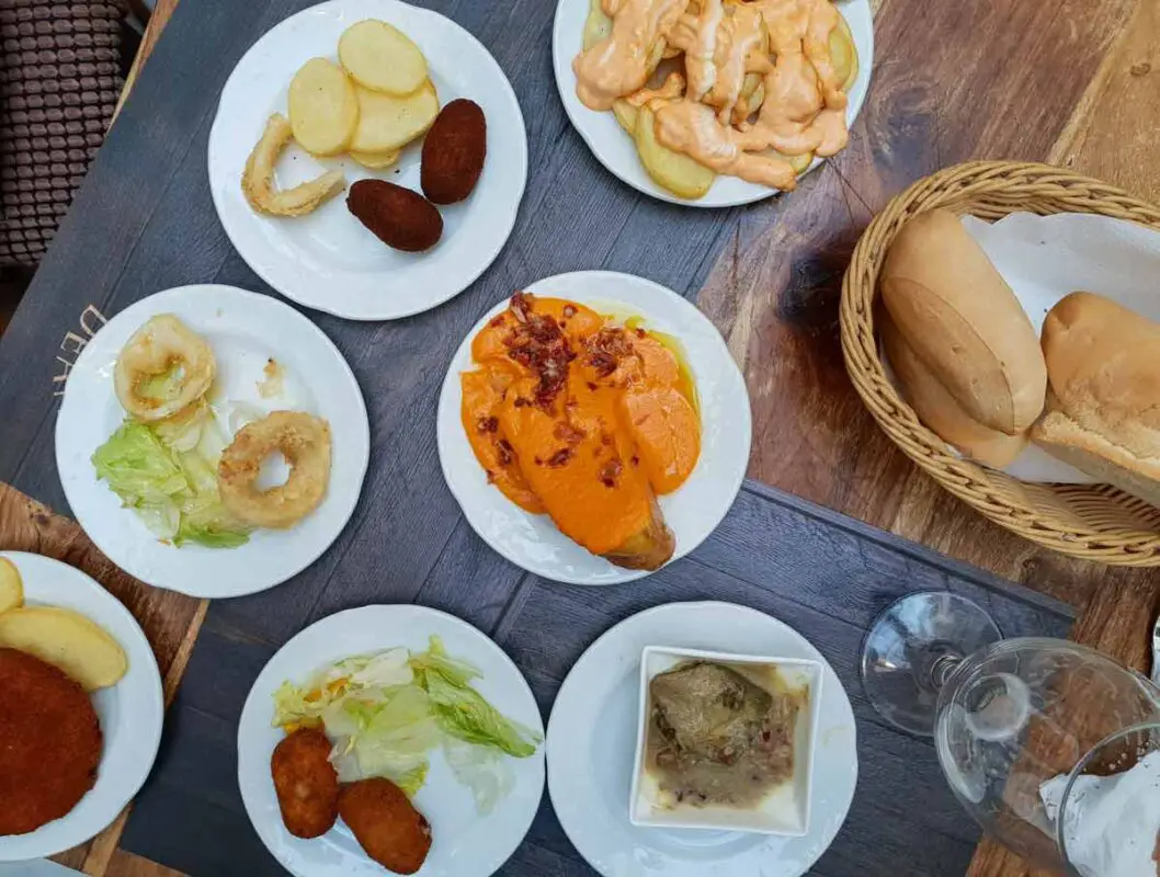 A table filled with small white plates, each with a different tapa in it