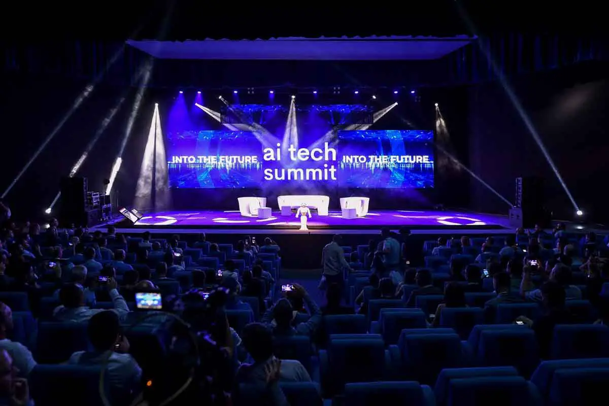 The stage at the AI tech summit in Malaga. It is blue and purple, and there is a white robot on the stage
