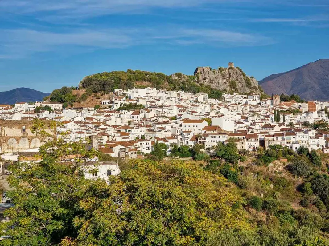 A view of Gaucin from a viewpoint. You can see the entire village high up on a hill, and the castle standing on the top, built on a cliff.